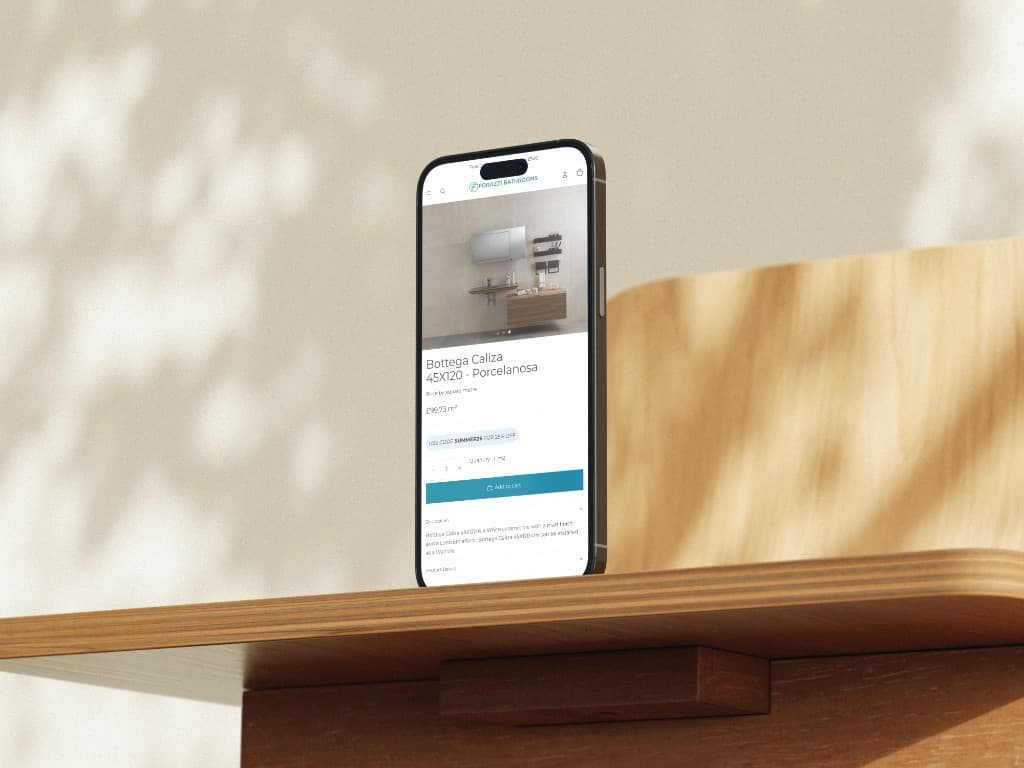 A phone on a wooden shelf showing Bottega Caliza 45 by 120 centimetres, with a bathroom scene above the price